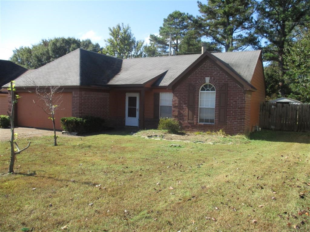 a small brick house with a yard and a wood fence