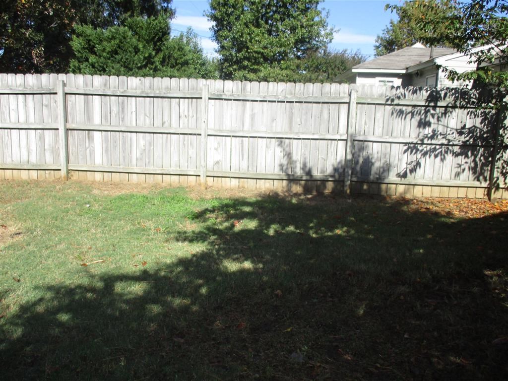 a white fence in a backyard with a house and a tree