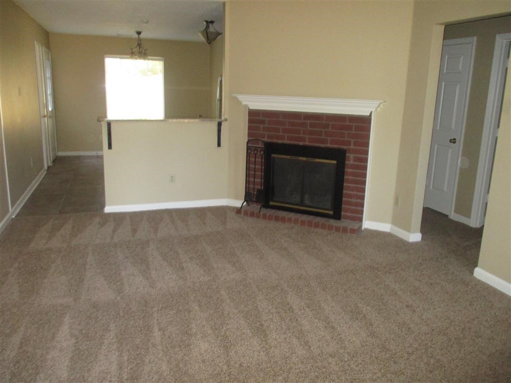 an empty living room with a red brick fireplace