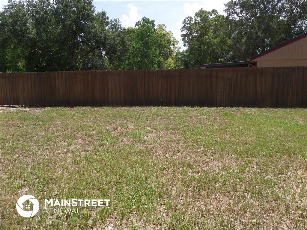 a backyard with a wooden fence and a grass field