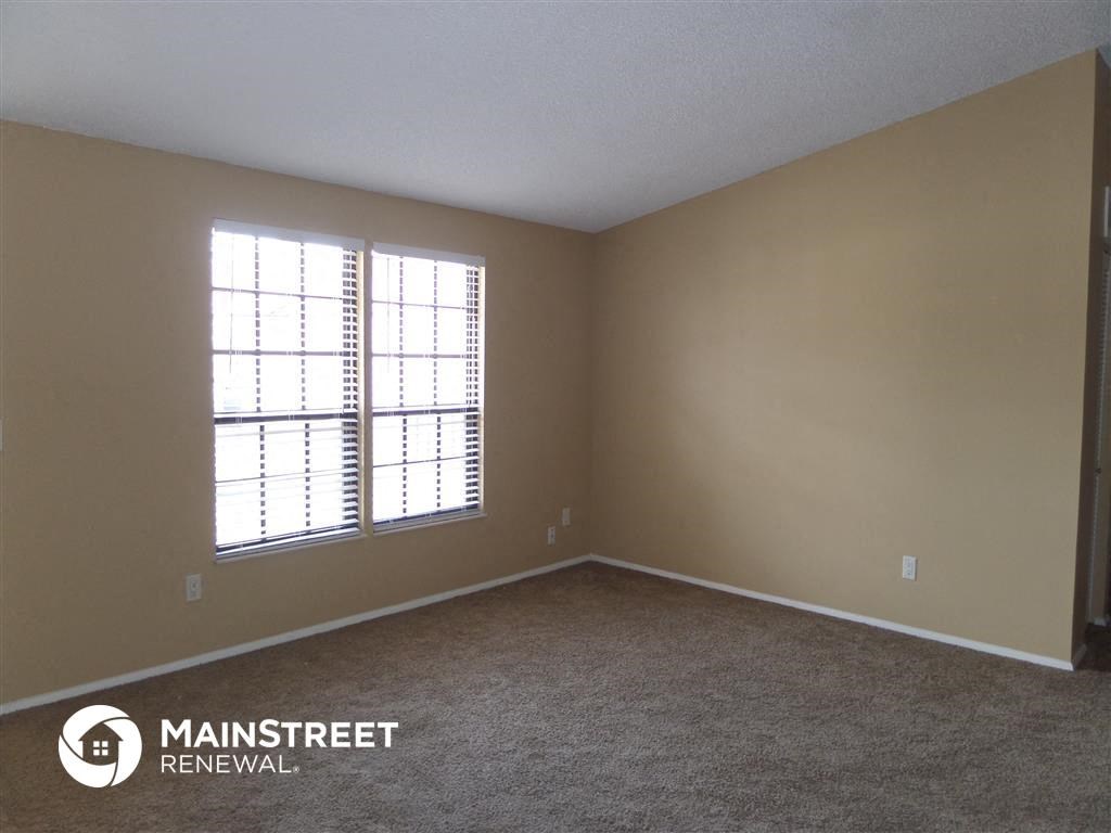 an empty bedroom with a window and carpet