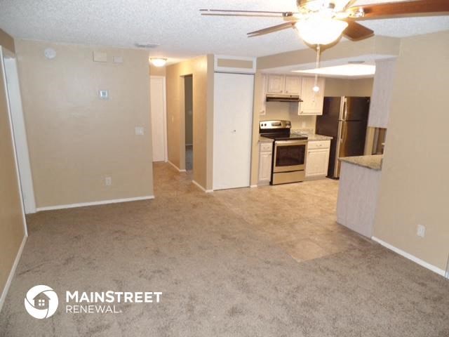 an empty living room and kitchen with a ceiling fan