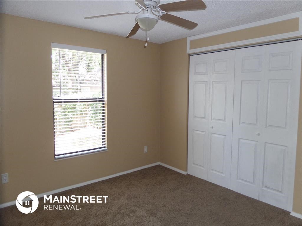 a bedroom with a ceiling fan and a window and two closets