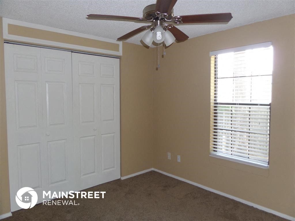 a bedroom with a ceiling fan and a closet and a window