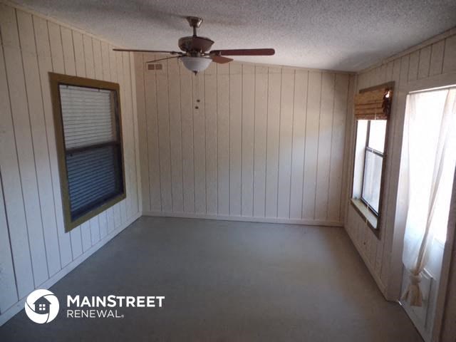 a small room with a ceiling fan and a window