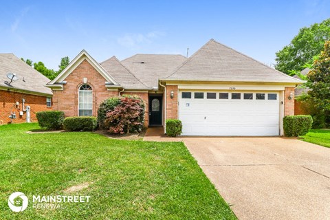 a brick house with a white garage door and a lawn