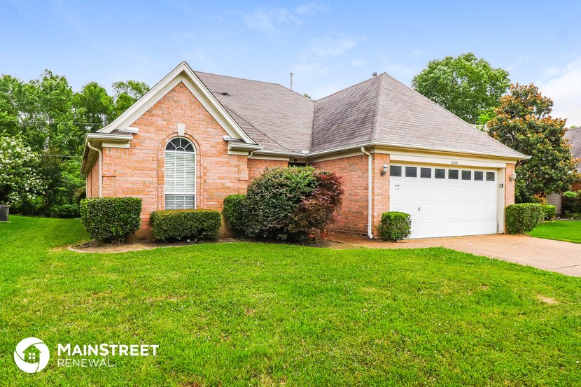 the front of a brick house with a lawn and a white garage door