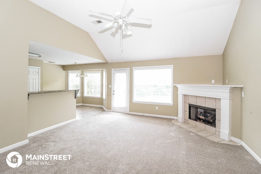 an empty living room with a fireplace and a ceiling fan