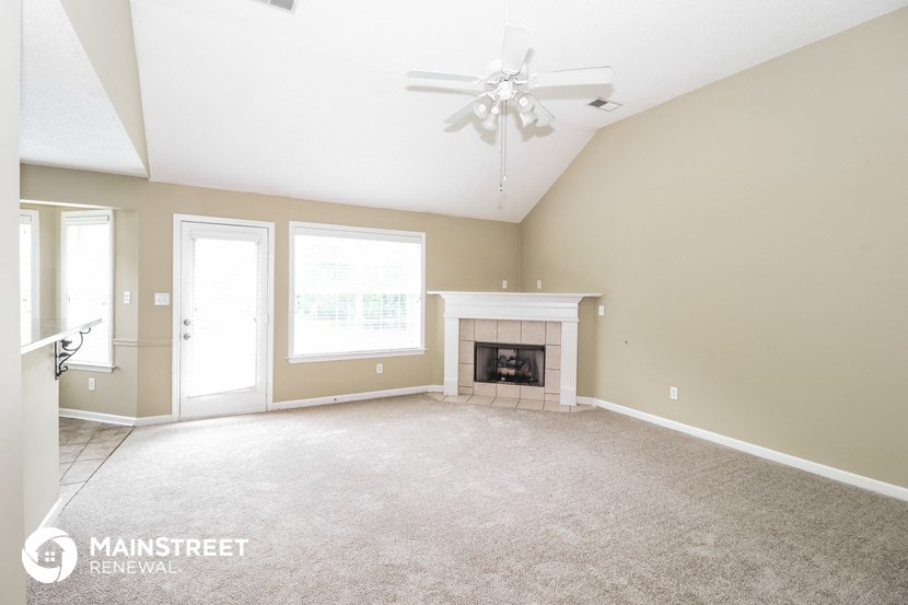 an empty living room with a fireplace and a ceiling fan