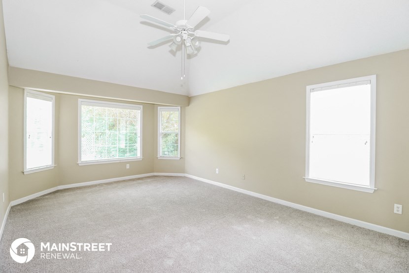 the master bedroom with carpet and a ceiling fan