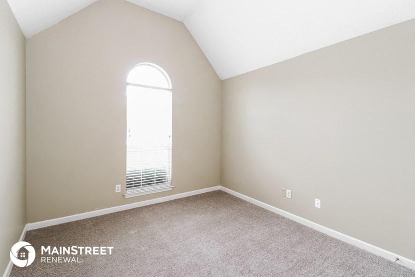 a bedroom with a large window and carpeting