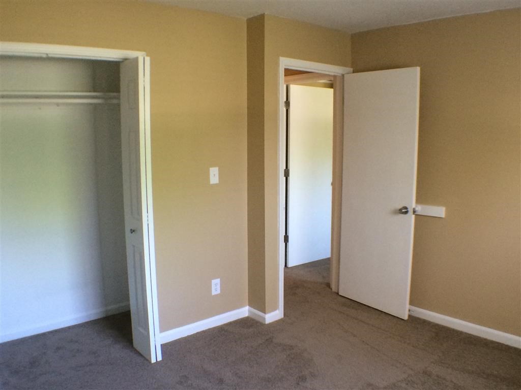 an empty room with an open door and a closet