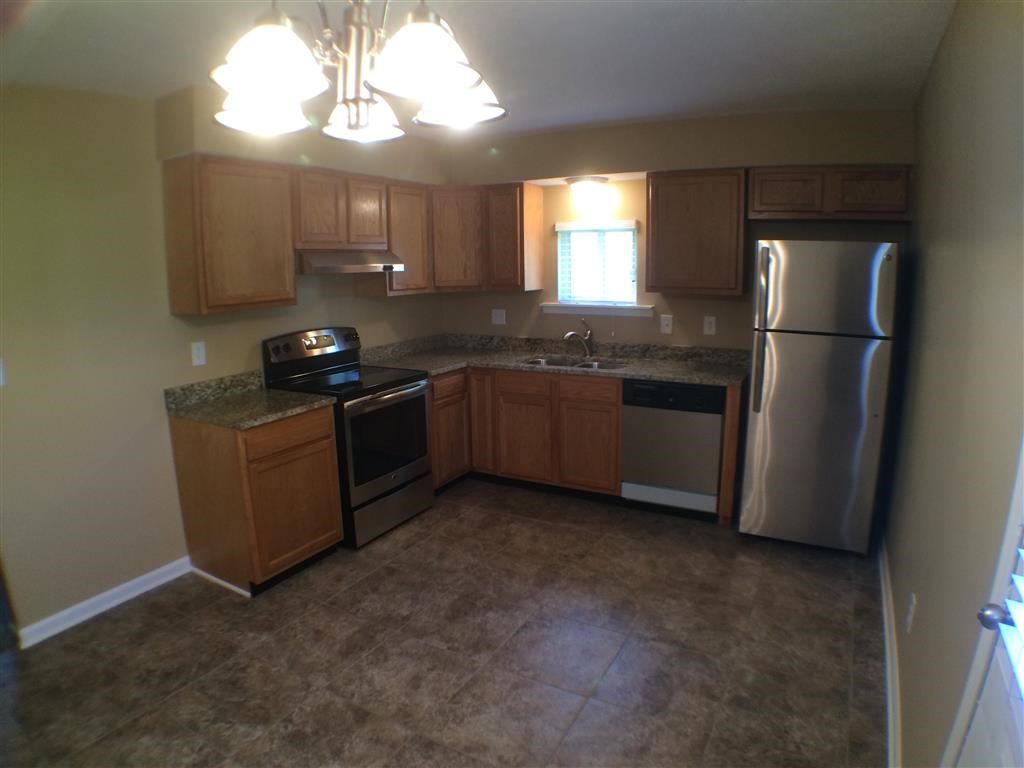 an empty kitchen with stainless steel appliances and wooden cabinets