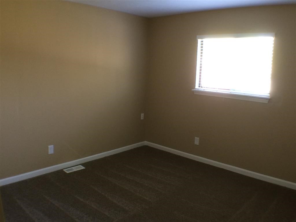 a empty room with a window and wooden floors