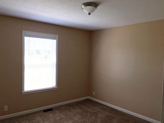 an empty room with a window and a ceiling light