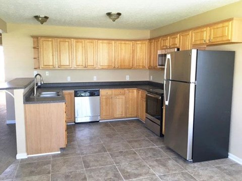 a kitchen with wooden cabinets and a stainless steel refrigerator