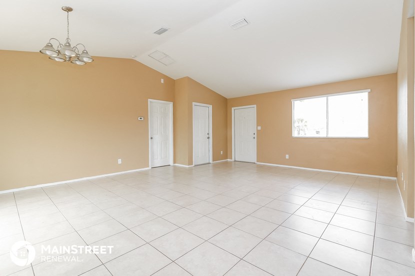 an empty living room with tan walls and a white tile floor