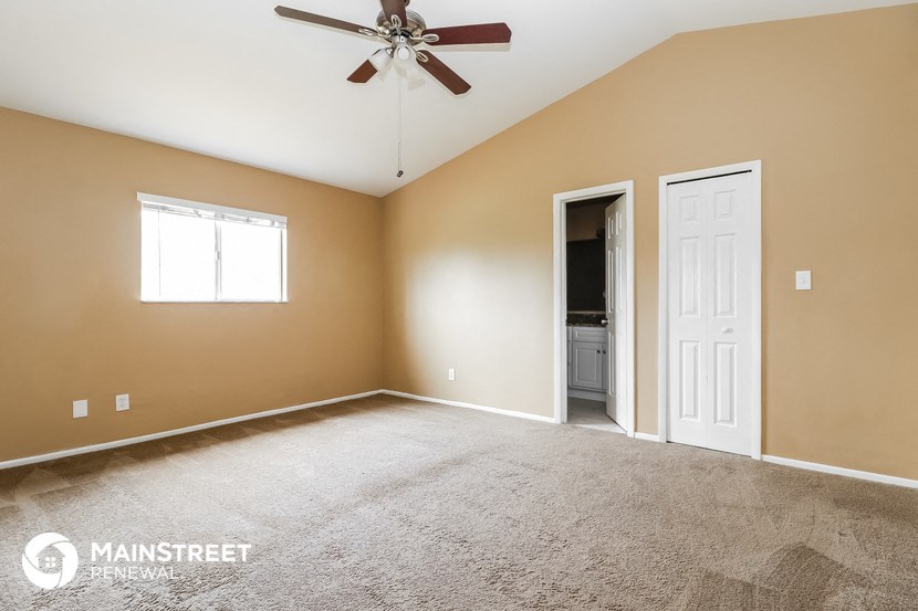 the master bedroom has carpeted floors and a ceiling fan