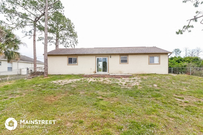 a small tan house on a grassy hill with trees