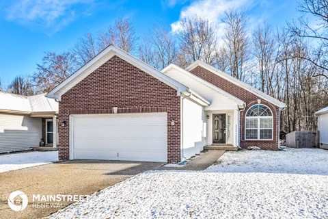a brick home with a white garage door in the snow