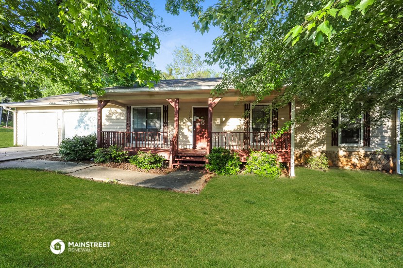 the front of a house with a porch and a lawn