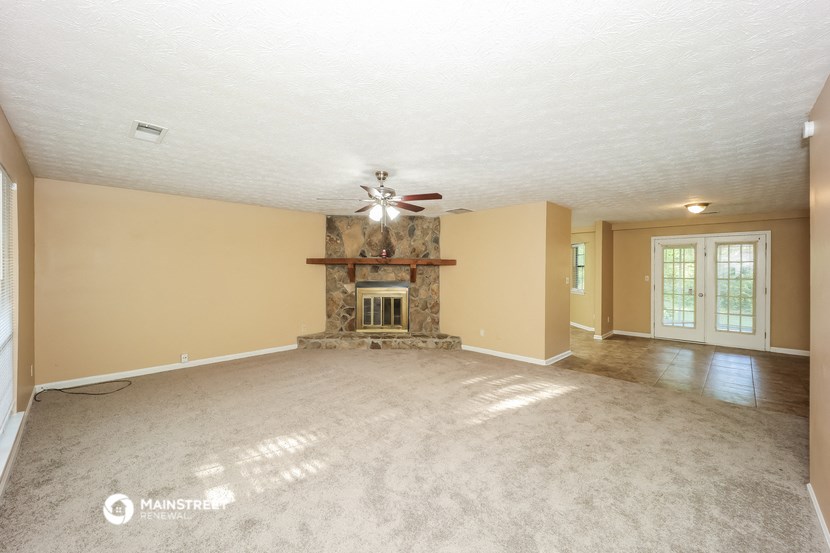an empty living room with a fireplace and a ceiling fan