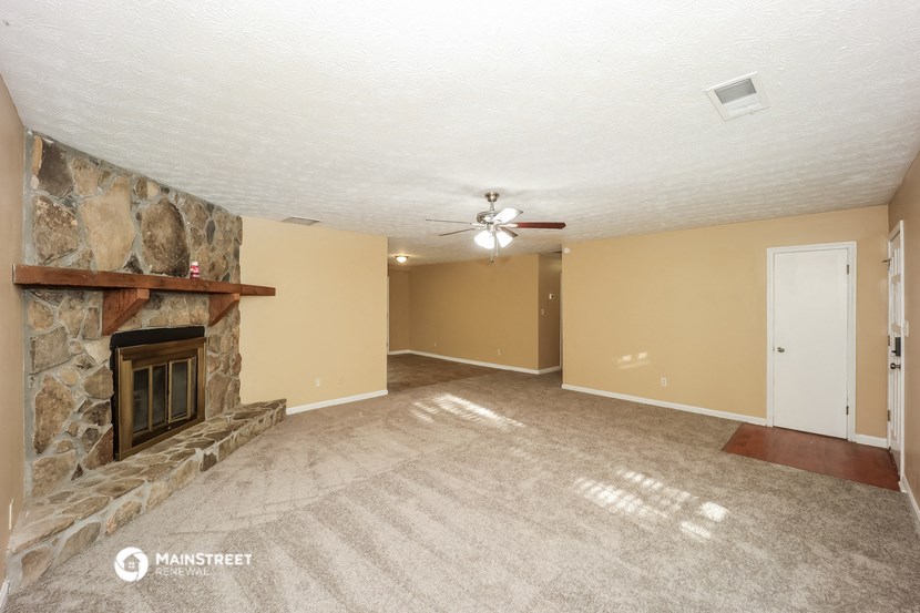 an empty living room with a fireplace and a ceiling fan