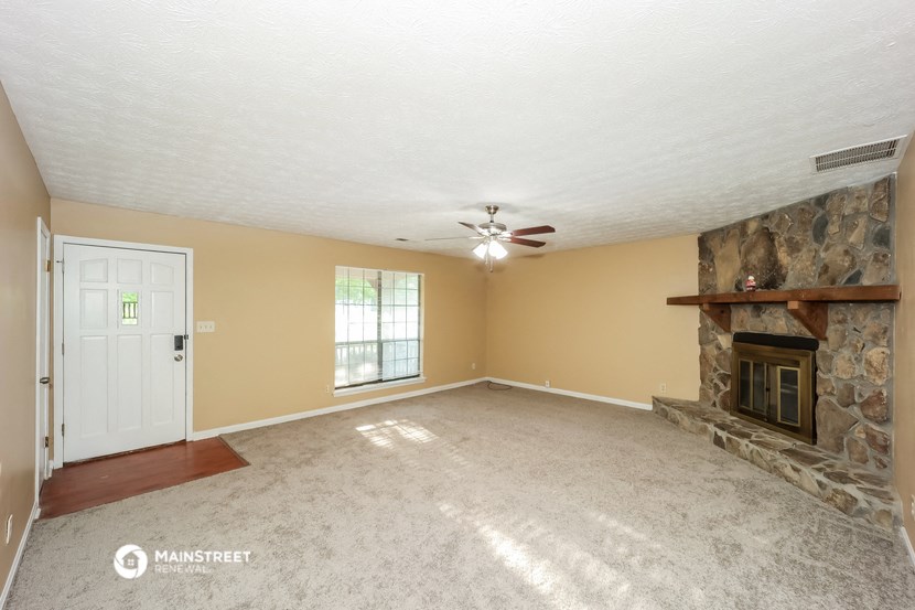 an empty living room with a fireplace and a ceiling fan