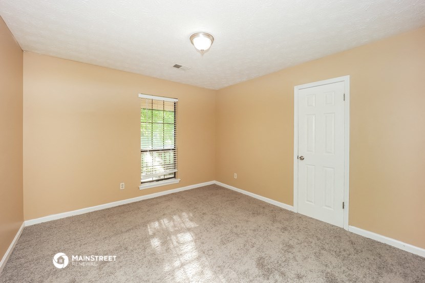 an empty living room with a white door and a window