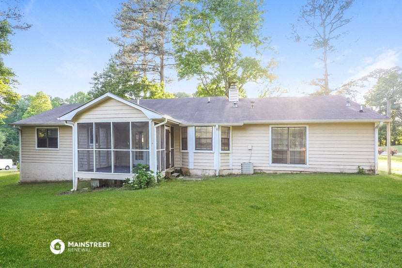 the front of a white house with a lawn and trees