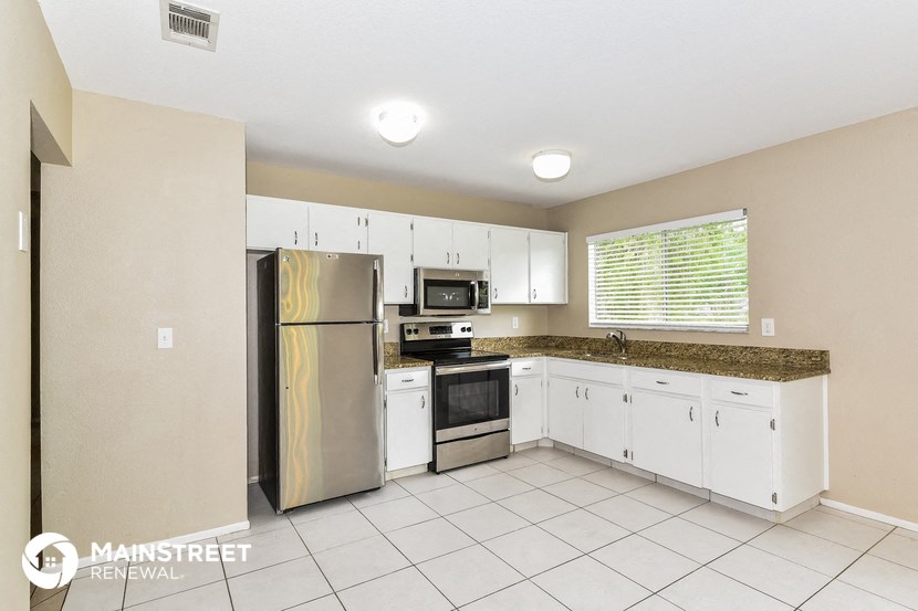 a kitchen with white cabinets and a stainless steel refrigerator