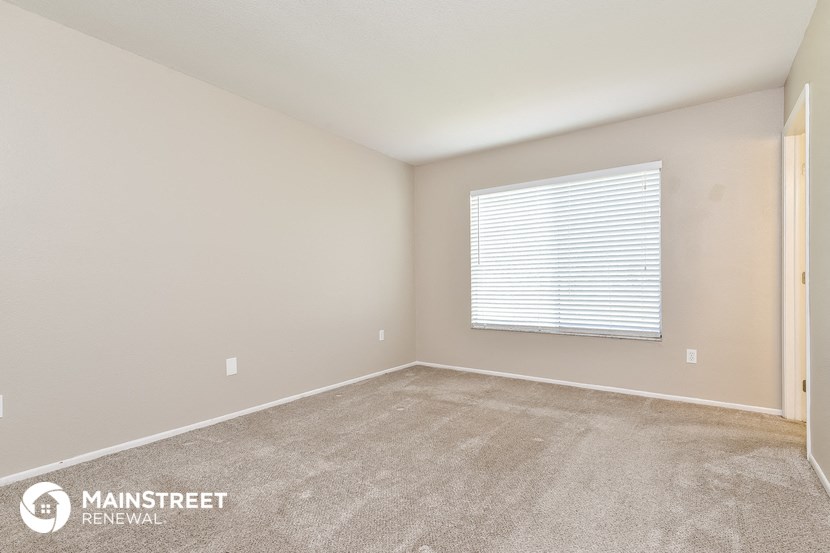 the spacious living room has carpeted floors and a window