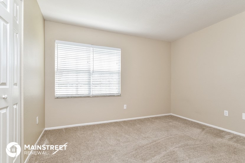 the spacious bedroom has carpeted floors and a large window