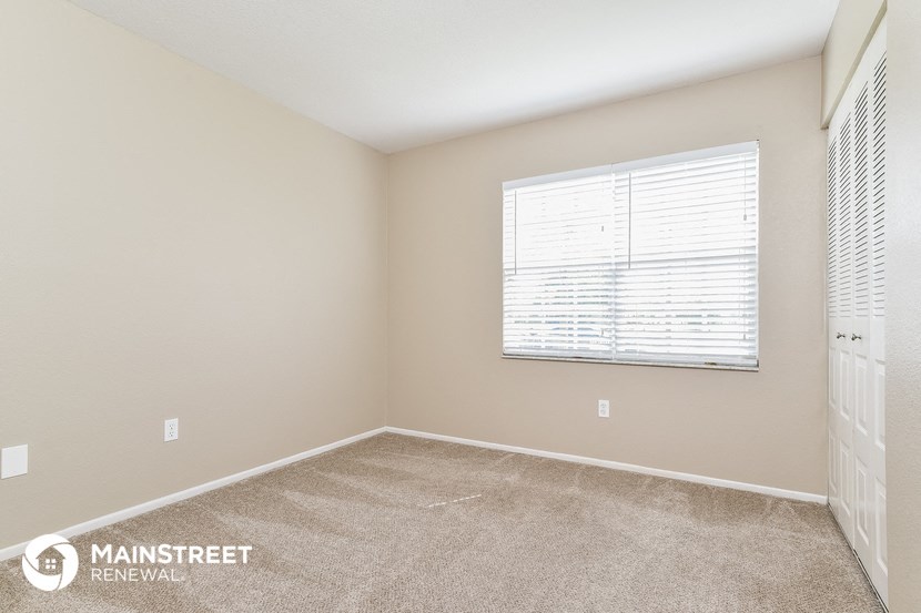 the spacious living room with a large window and carpeted flooring