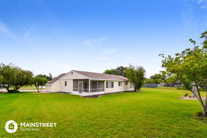 a small white house sitting in the middle of a green field