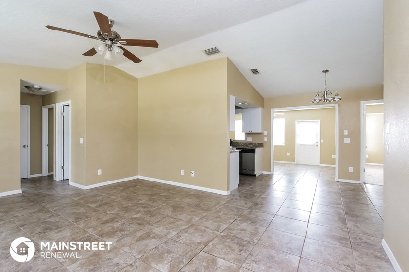 a large living room with tile flooring and a ceiling fan