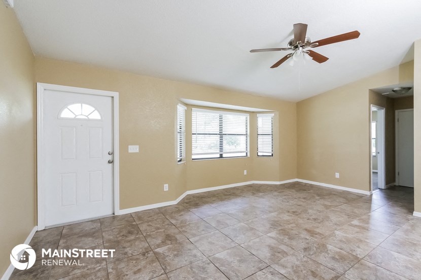 an empty living room with a white door and a ceiling fan