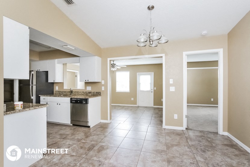 an open kitchen and living room with tile floors and beige walls