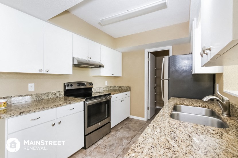 a kitchen with white cabinets and granite counter tops and stainless steel appliances