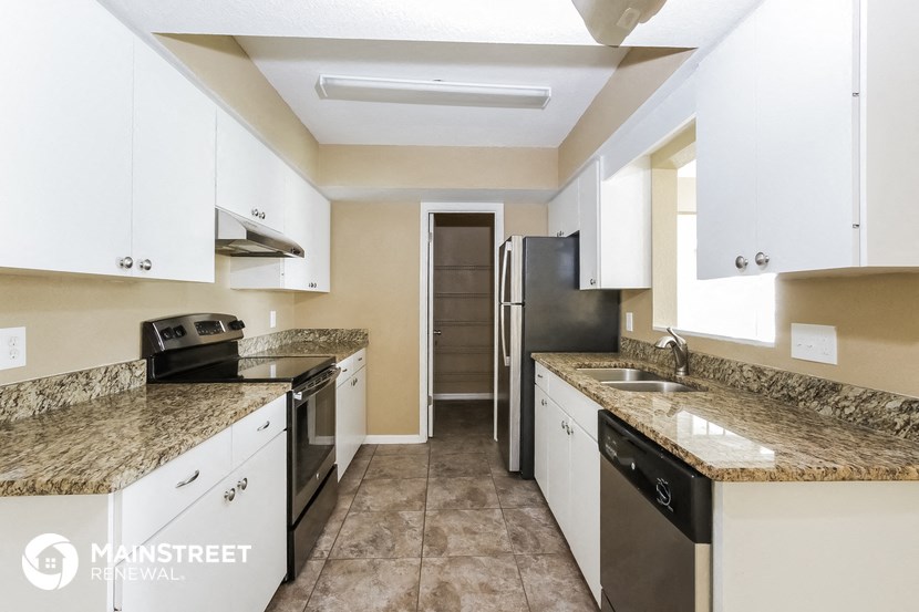 a kitchen with white cabinets and granite counter tops and a stainless steel refrigerator