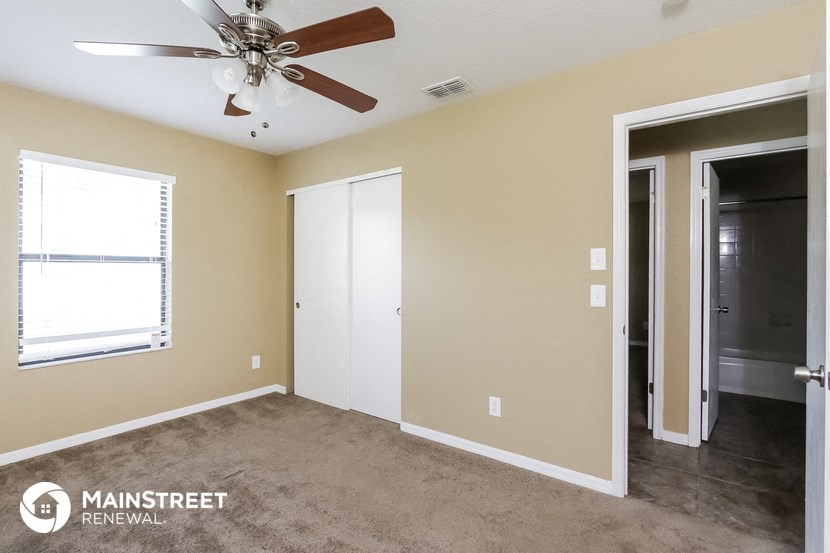 a living room with a ceiling fan and a door to a closet