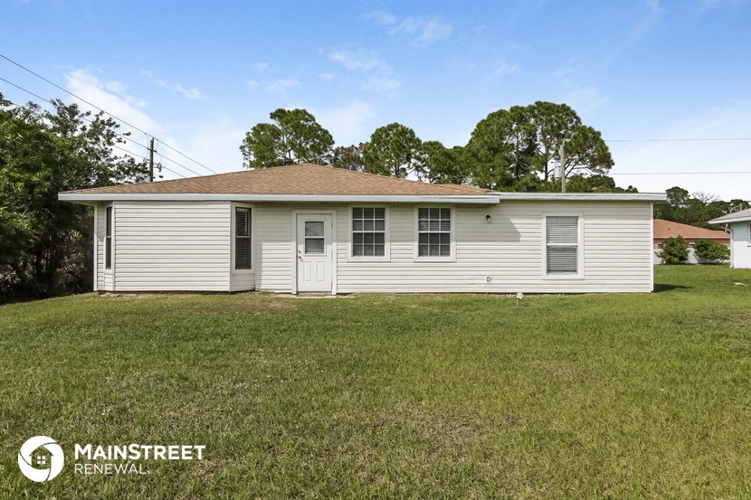 a small white mobile home in a grassy yard