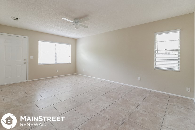 the spacious living room with tile flooring and a ceiling fan