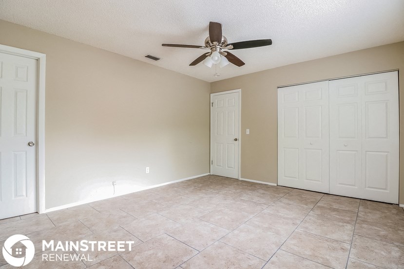 an empty living room with a ceiling fan and tile floor