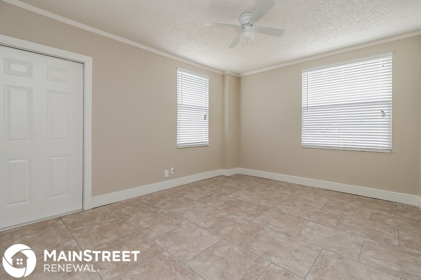 the spacious living room with a ceiling fan and tile flooring