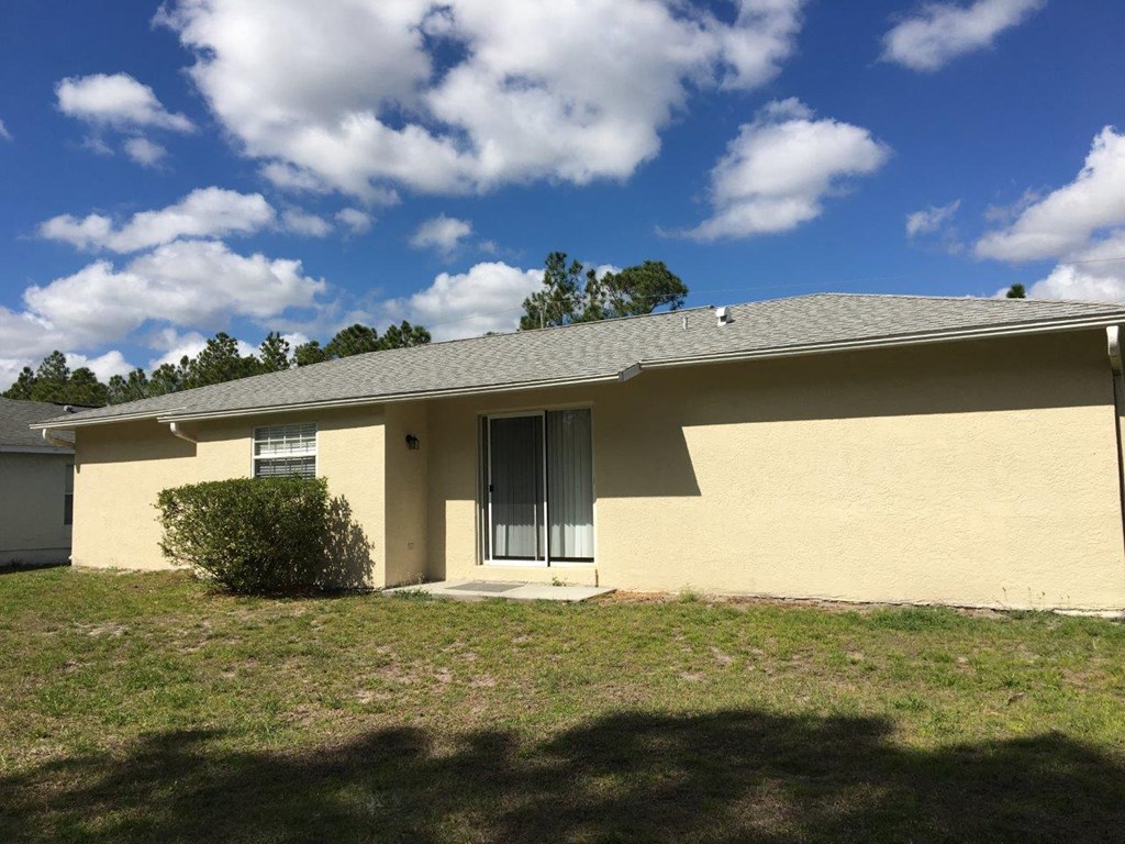 the front of a yellow house with a green lawn