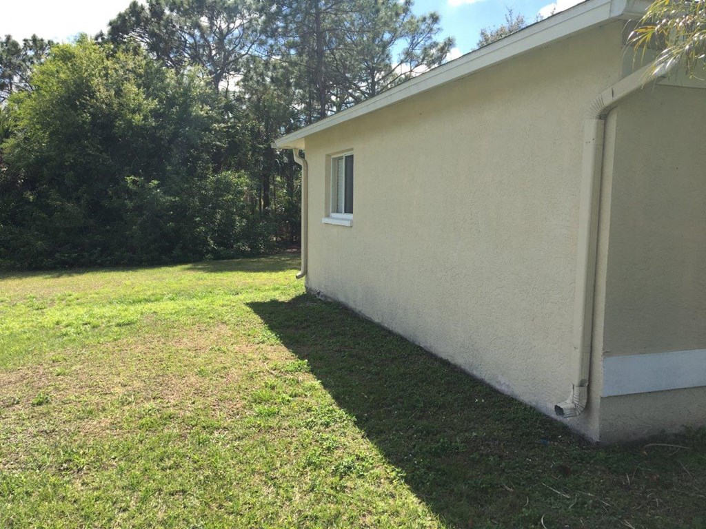 a side view of a house with a lawn and trees