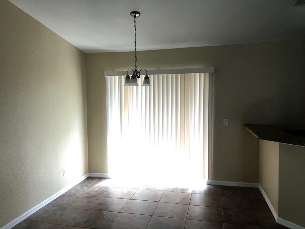 an empty living room with a large window and a chandelier
