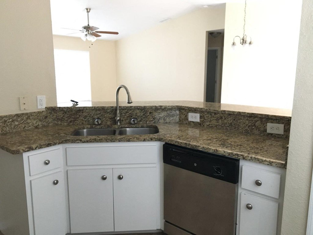 a kitchen with white cabinets and a granite counter top