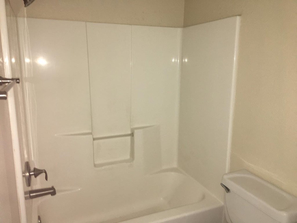 a white bathroom with a tub and a toilet